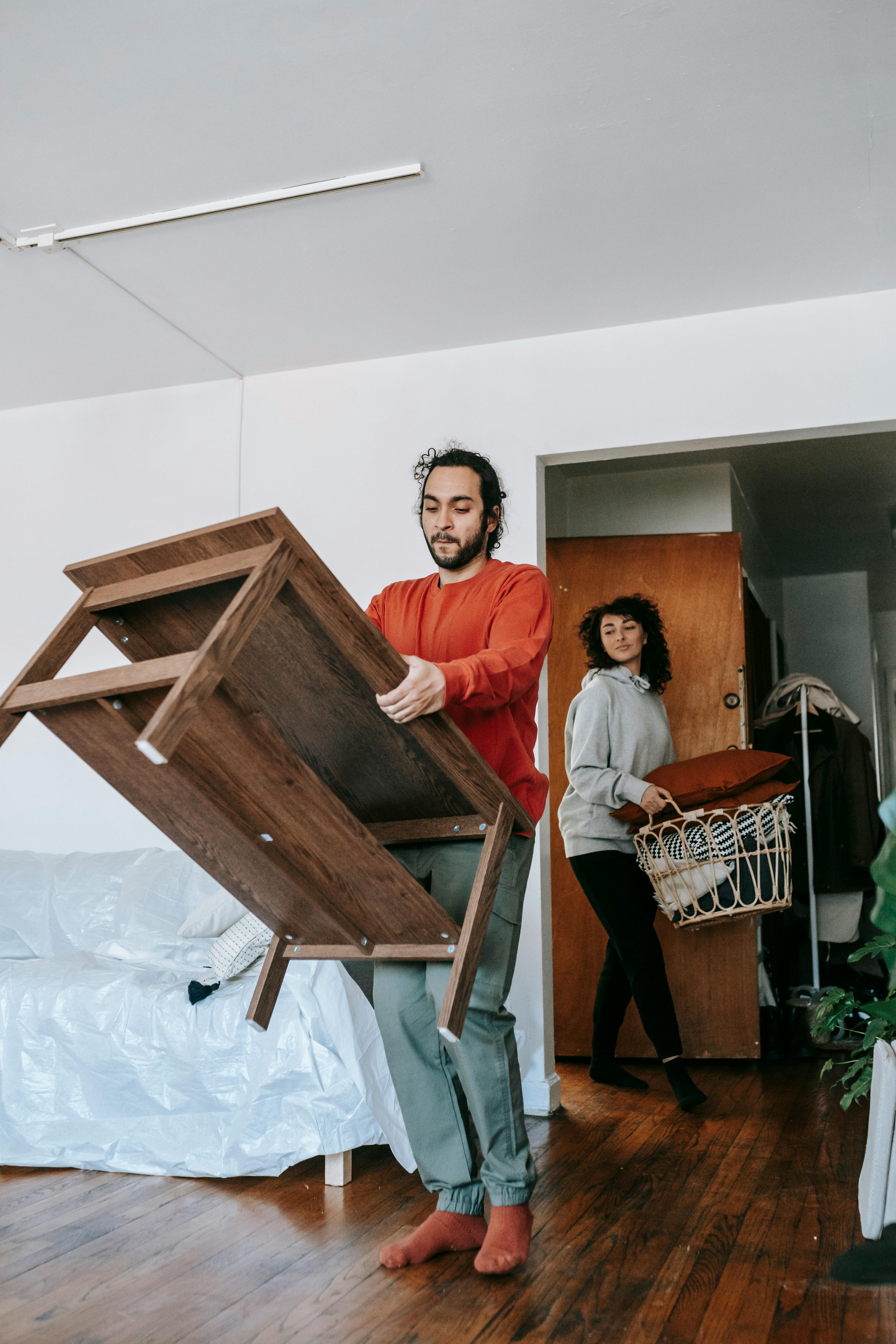 Movers lifting furniture over hardwood floor