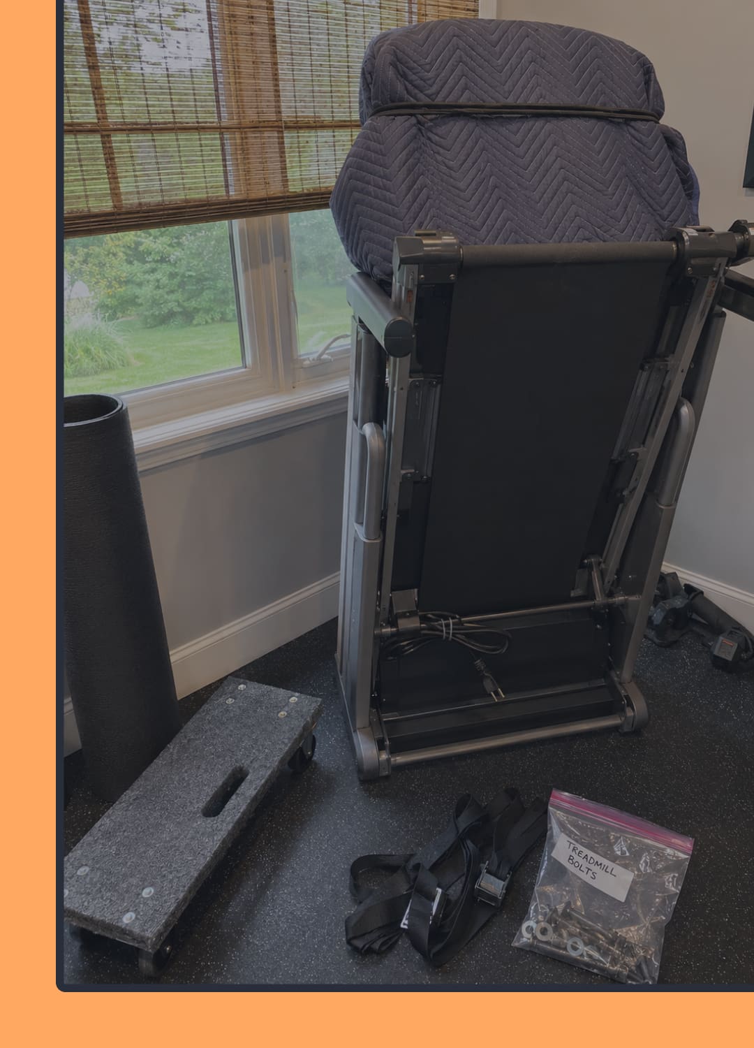 Treadmill prepared for moving with blankets, dolly, straps, and labeled hardware bag